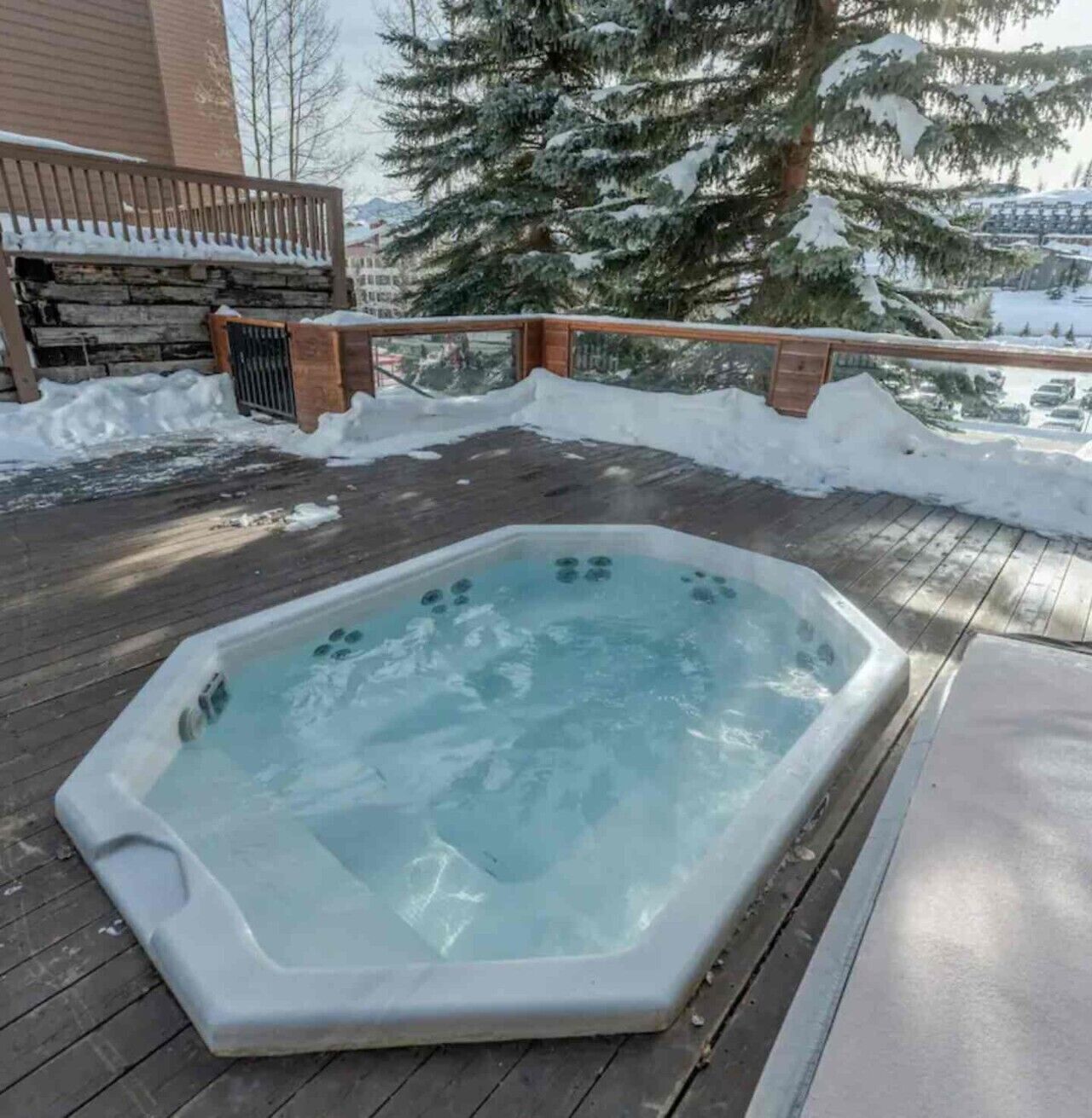 Ein Whirlpool auf einer Holzterrasse, umgeben von Schnee.