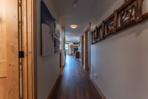 A hallway with wooden flooring, framed pictures on the walls, and a door on the left. - Evergreen Paradise - Hot Tub, Fireplace, Walk to (Crested Butte)