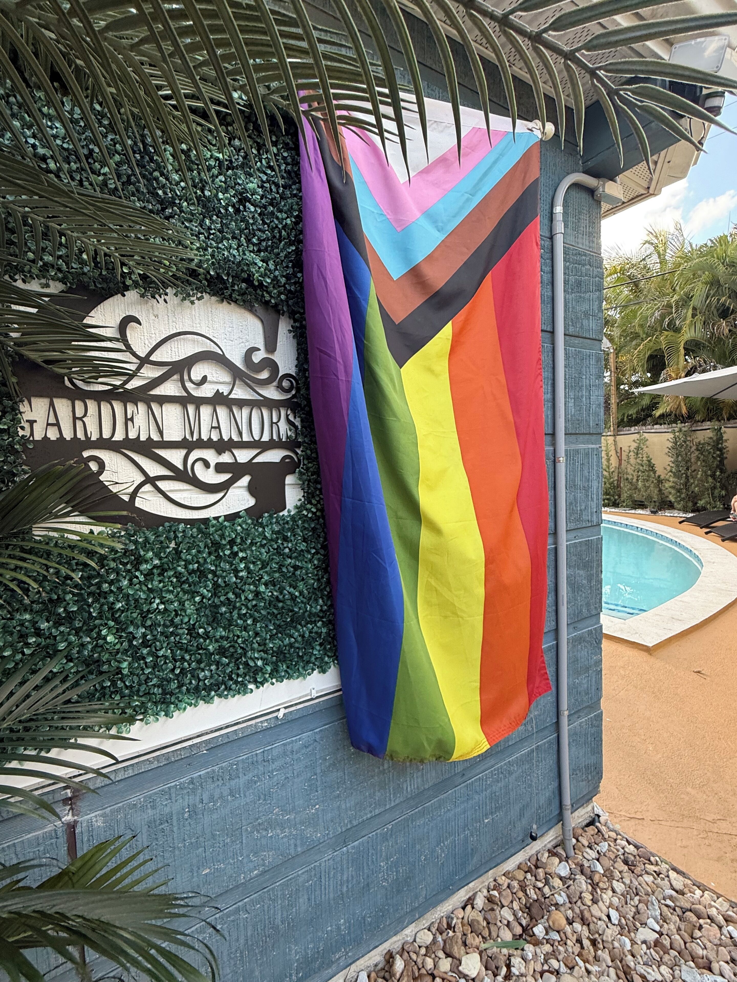 Un letrero con el texto 'GARDEN MANORS' y una bandera colorida.