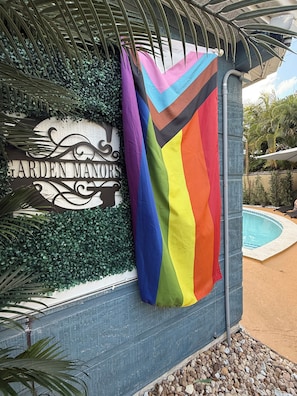 Un letrero con el texto 'GARDEN MANORS' y una bandera colorida.