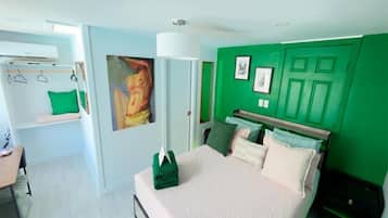Un dormitorio con cama, pared verde, un cuadro y armario.
