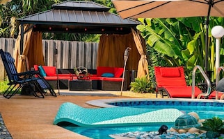 Una piscina al aire libre, sombrillas, sillones reclinables de piscina