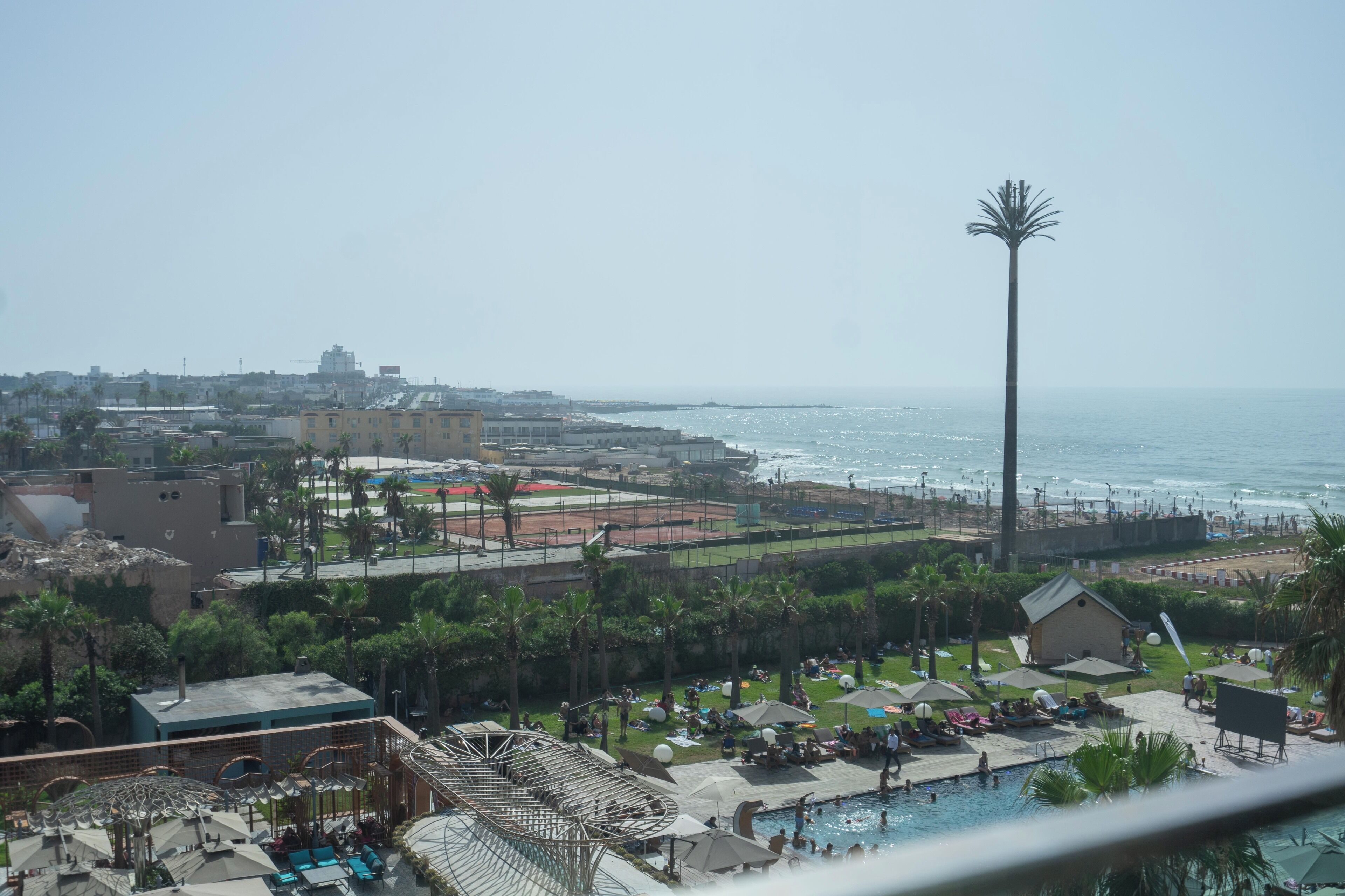 Een resort met zwembad, strand en een hoge palmpalm.