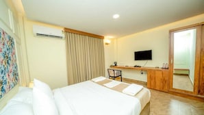 A hotel room with a bed, a desk, a chair, a TV, and a wardrobe. - The Clock Tower Inn (Bengaluru)