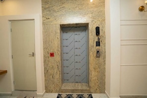 An elevator with a patterned wall, a door, and a wall-mounted light fixture. - The Clock Tower Inn (Bengaluru)