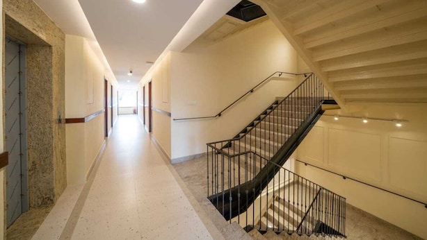 A hotel corridor with a staircase and a door on the left. - The Clock Tower Inn (Bengaluru)