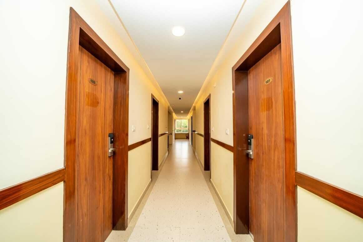 A hotel hallway with wooden doors, a tiled floor, and a ceiling light.