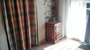 A room with a checkered curtain, a wooden cabinet, and a tiled floor.