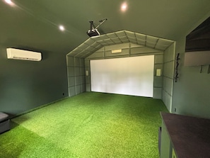 Quarto com carpete verde, porta branca e ar condicionado fixado na parede.