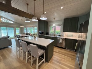 A modern kitchen with a central island, stainless steel appliances, and a view of a lake. - Luxury Lakefront | Golf Sim & Theatre | Dock (Westport)