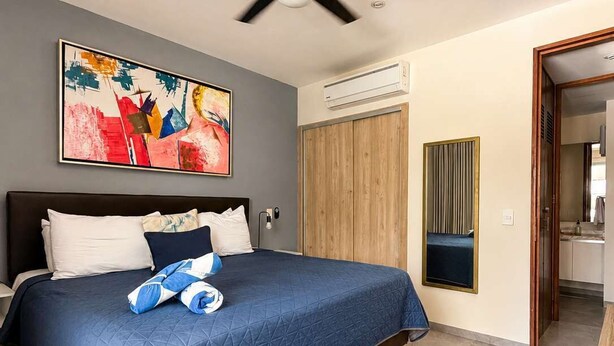 A hotel room with a bed, a ceiling fan, an air conditioning unit, and a painting on the wall. - Quiet Pool-View 1BR Near 5th Avenue (Playa del Carmen)