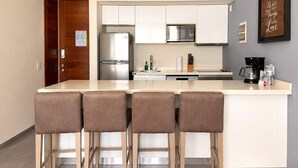 A modern kitchen with a central island, bar stools, stainless steel appliances, and a wall-mounted air conditioner. - Quiet Pool-View 1BR Near 5th Avenue (Playa del Carmen)