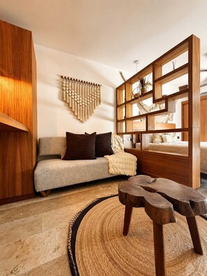 A modern living room with a sofa, wooden accents, a woven rug, and a unique wooden coffee table. - Quiet Studio w Rooftop Pool near DAC Market (Playa del Carmen)