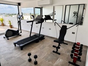 Ein Fitnessstudio mit Laufbändern, einer Hantelbank, Kurzhanteln und einem Spiegel.