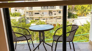 Un balcón con mesa y sillas, vista hacia una zona residencial y un edificio con balcones.