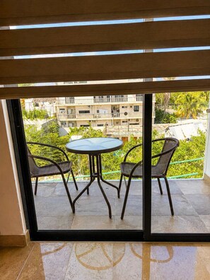Ein Balkon mit Tisch und Stühlen, Blick auf eine Wohngegend und ein Gebäude mit Balkonen.