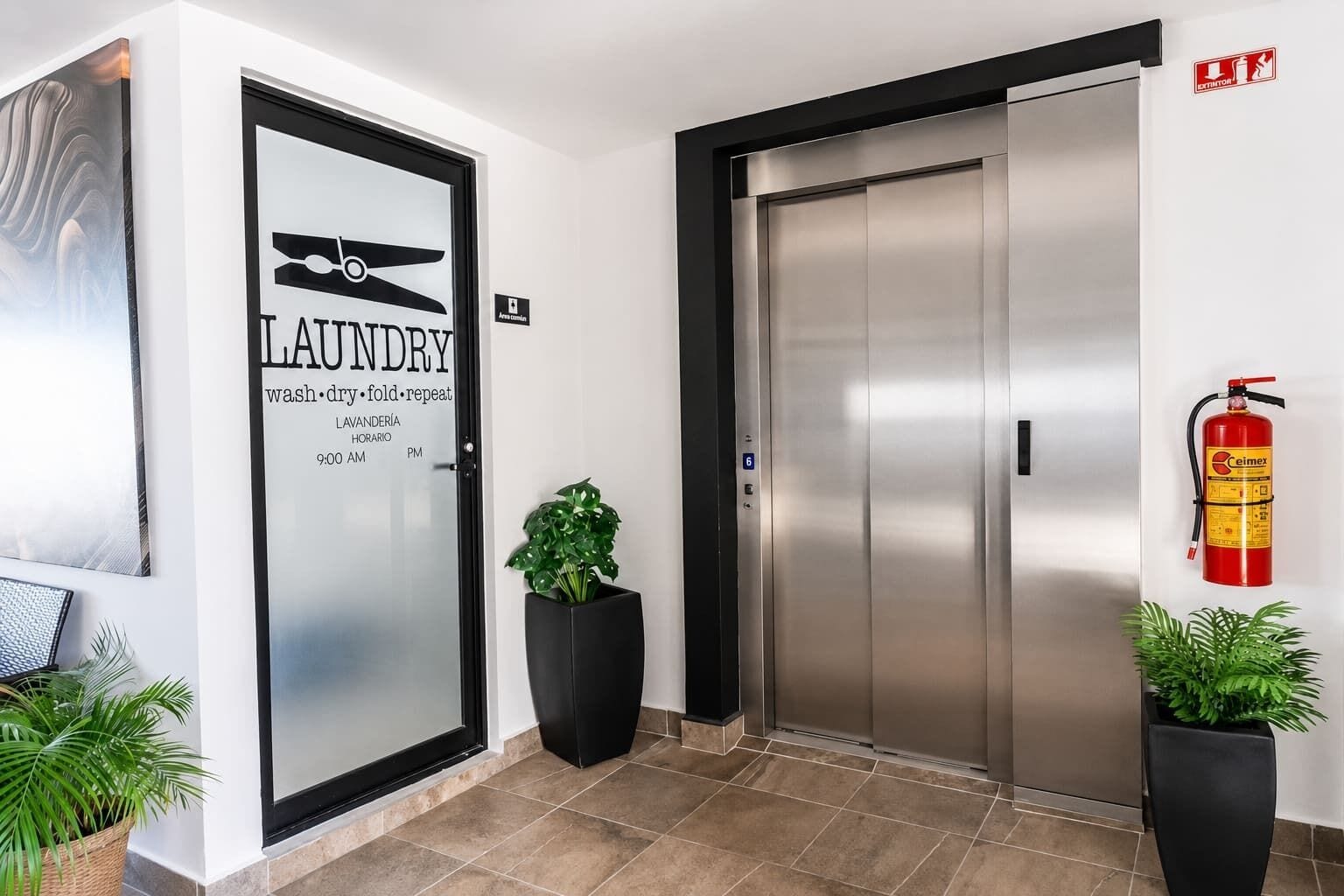 Entrada de un hotel con una puerta de vidrio esmerilado que indica 'LAUNDRY' y un extintor de incendios en la pared.