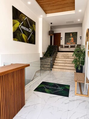 Ein Empfangsbereich mit einem Holztisch, einer Treppe und einer Buddha-Statue an der Wand.