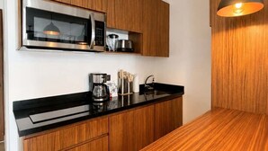 Uma cozinha moderna com armários de madeira, bancada preta e luminária pendente.