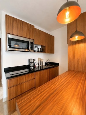 Eine moderne Küche mit Holzschnitzereien, einer schwarzen Arbeitsplatte und einer hängenden Pendelleuchte.