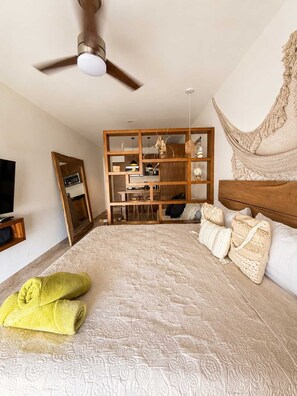 Ein Schlafzimmer mit einem Bett, einem Deckenventilator, einer Hängematte und einem fest eingebauten Holzregal.