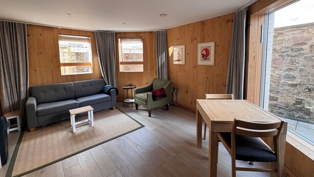 Une pièce aux murs en bois, avec un canapé, une table et des chaises.