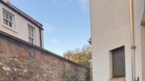 Un mur de pierre, un banc, une fenêtre et une porte.