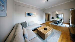 A modern living room with a sectional sofa, a wooden coffee table, and a dining area with a round table and chairs. - Elenas Luxury Apartment/Panoramic Acropolis View (Athina)