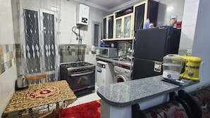 A compact kitchen with a gas stove, oven, microwave, refrigerator, and washing machine. - One Minute To The Sea-Asafra Beach 
Fast WiFi - AC - Family Friendly (Alexandria Governorate)