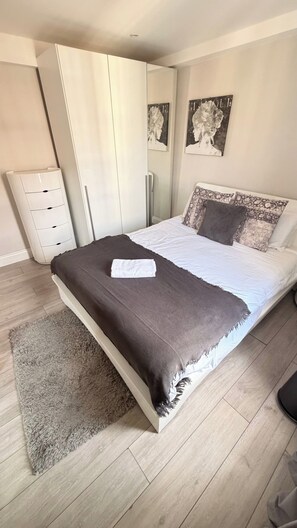 A bedroom with a bed, a wardrobe, a dresser, and a rug. - Marble Arch Elevator Ac - 3 Bedroom Apartment (London)