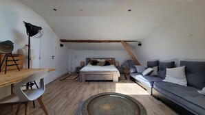A loft bedroom with a skylight, a bed, a sofa, a dining table, and a chair. - Family home on the banks of the Saône, 30 minutes from Lyon (Massieux)