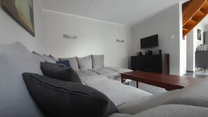 A modern living room with a sofa, a wooden coffee table, a TV, and a cabinet. - Familienfreundliches Ferienhaus mit Garten im Hafendorf Muritz (Rechlin)