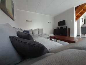 A modern living room with a sofa, a wooden coffee table, a TV, and a cabinet. - Familienfreundliches Ferienhaus mit Garten im Hafendorf Muritz (Rechlin)