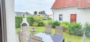 A patio with a table and chairs, a barbecue grill, and a car parked in the background. - Familienfreundliches Ferienhaus mit Garten im Hafendorf Muritz (Rechlin)