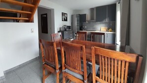 A dining area with a wooden table and chairs, a kitchen with modern appliances, and a staircase leading to an upper level. - Familienfreundliches Ferienhaus mit Garten im Hafendorf Muritz (Rechlin)