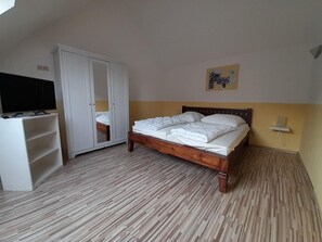 Ein Schlafzimmer mit einem Bett, einem Kleiderschrank, einem Fernseher und einem Bild an der Wand.