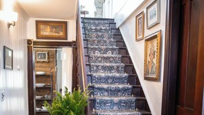 A staircase with patterned carpet, a potted plant, and a door with a wooden frame. - Lilac Inn Waddington (Waddington)