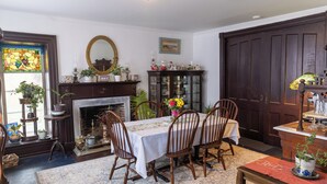 A dining room with a fireplace, wooden chairs, a table set for four, and a large mirror above the mantel. - Lilac Inn Waddington (Waddington)