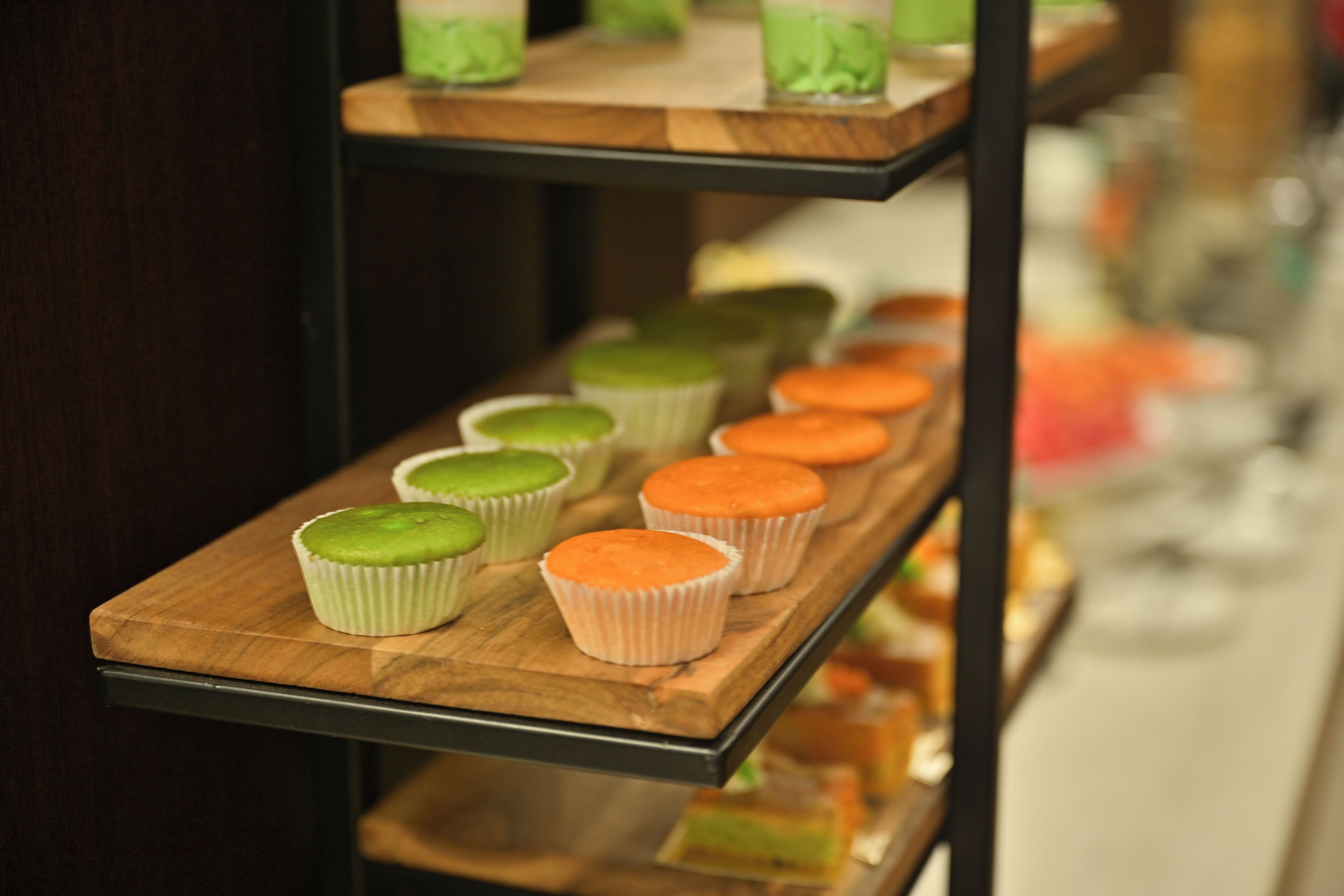 A wooden shelf with cupcakes in white paper cups.