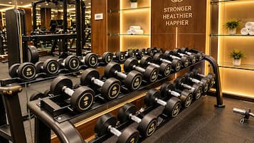 A gym with weightlifting equipment, including dumbbells and barbells, and a motivational slogan on the wall.