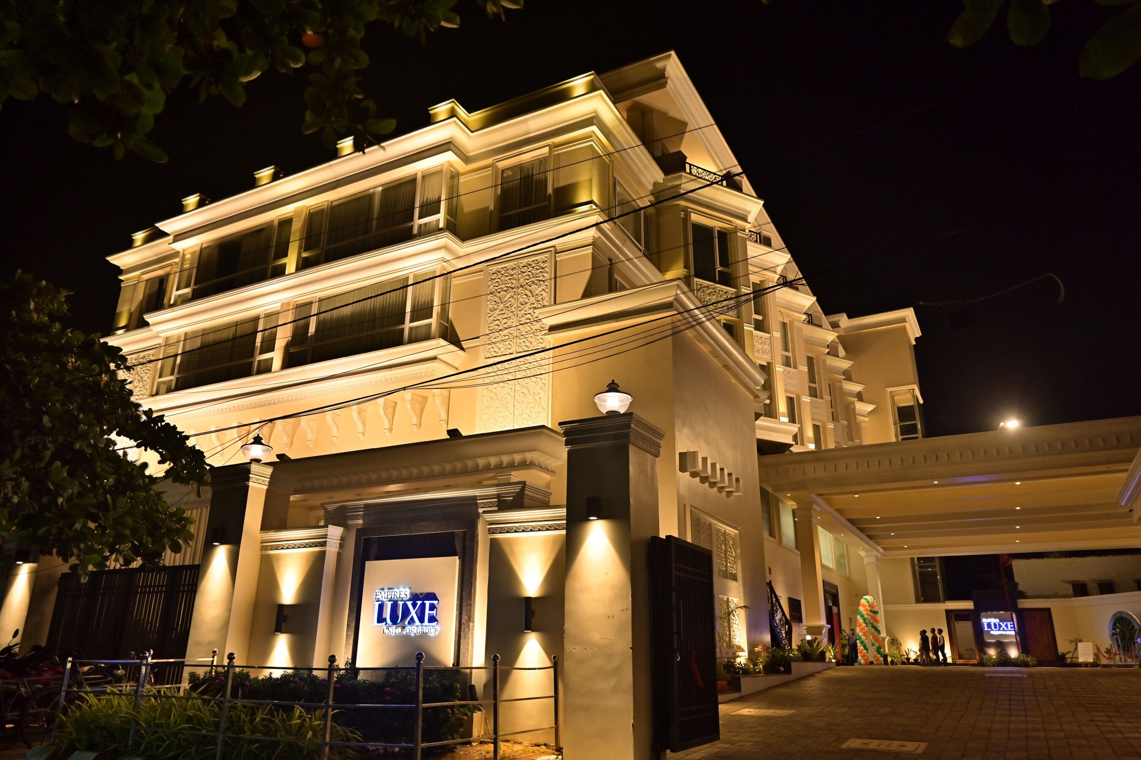 A hotel entrance with a prominent sign, a gated driveway, and a well-lit facade.