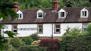Um edifício tradicional com várias janelas e uma placa com o texto 'LUMFORD COTTAGES'.