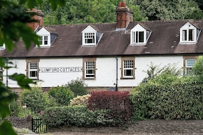 Ein traditionelles Gebäude mit zahlreichen Fenstern und einem Schild, auf dem 'LUMFORD COTTAGES' steht.