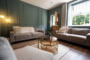 Ein Wohnzimmer mit zwei Sofas, einem Couchtisch und einem Fenster mit Vorhängen.