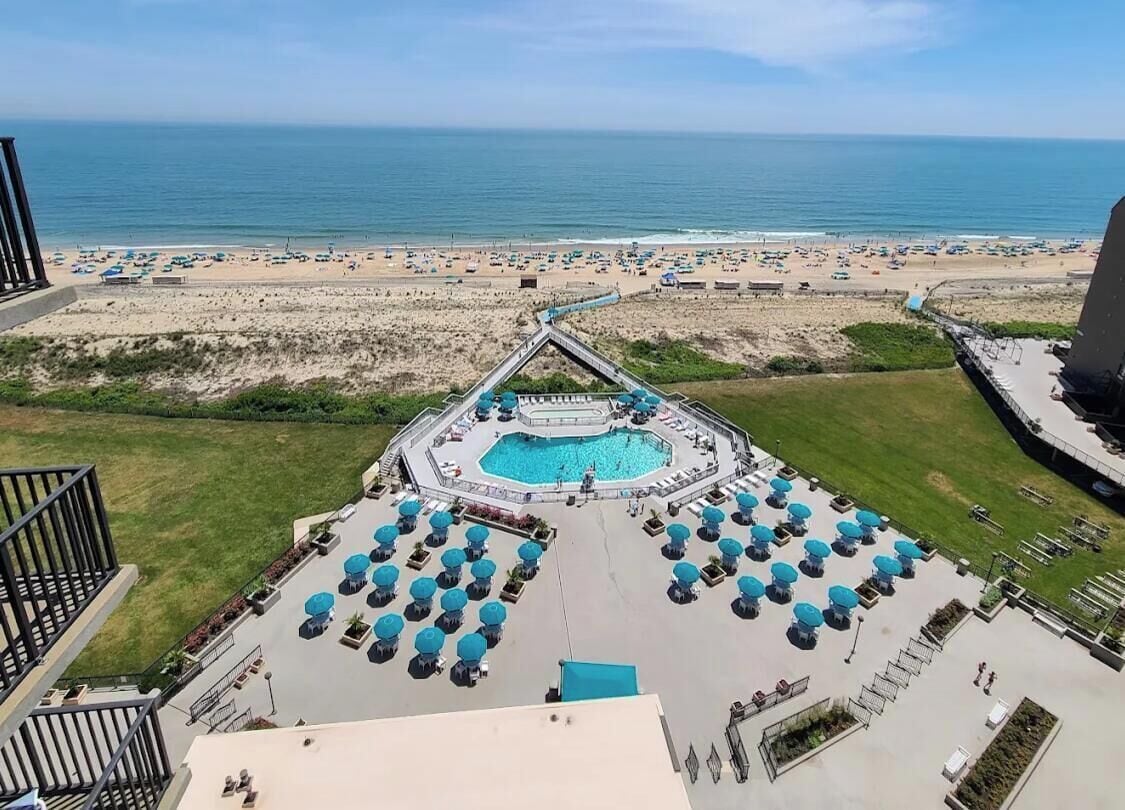 A rooftop pool area with a view of the beach and ocean.