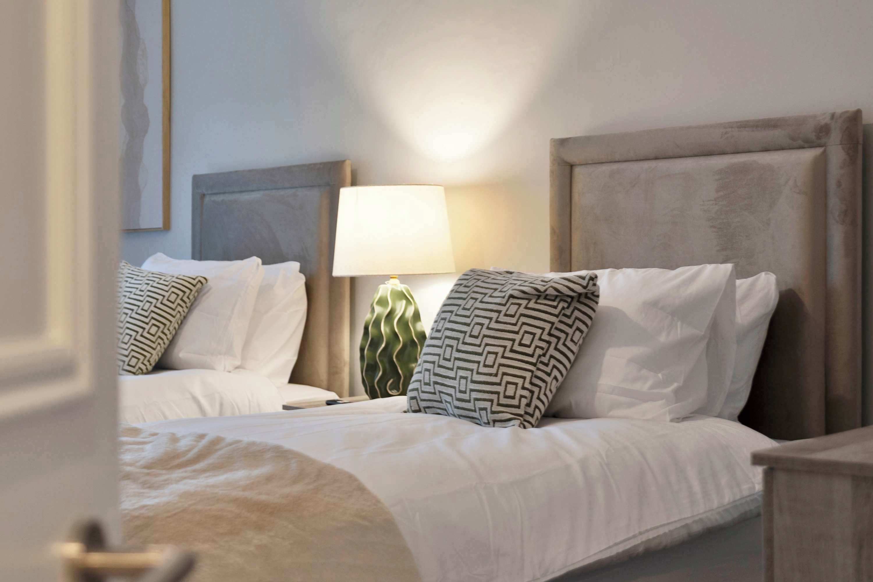 Ein Hotelzimmer mit zwei Betten, einer Lampe und einem Wandbild.