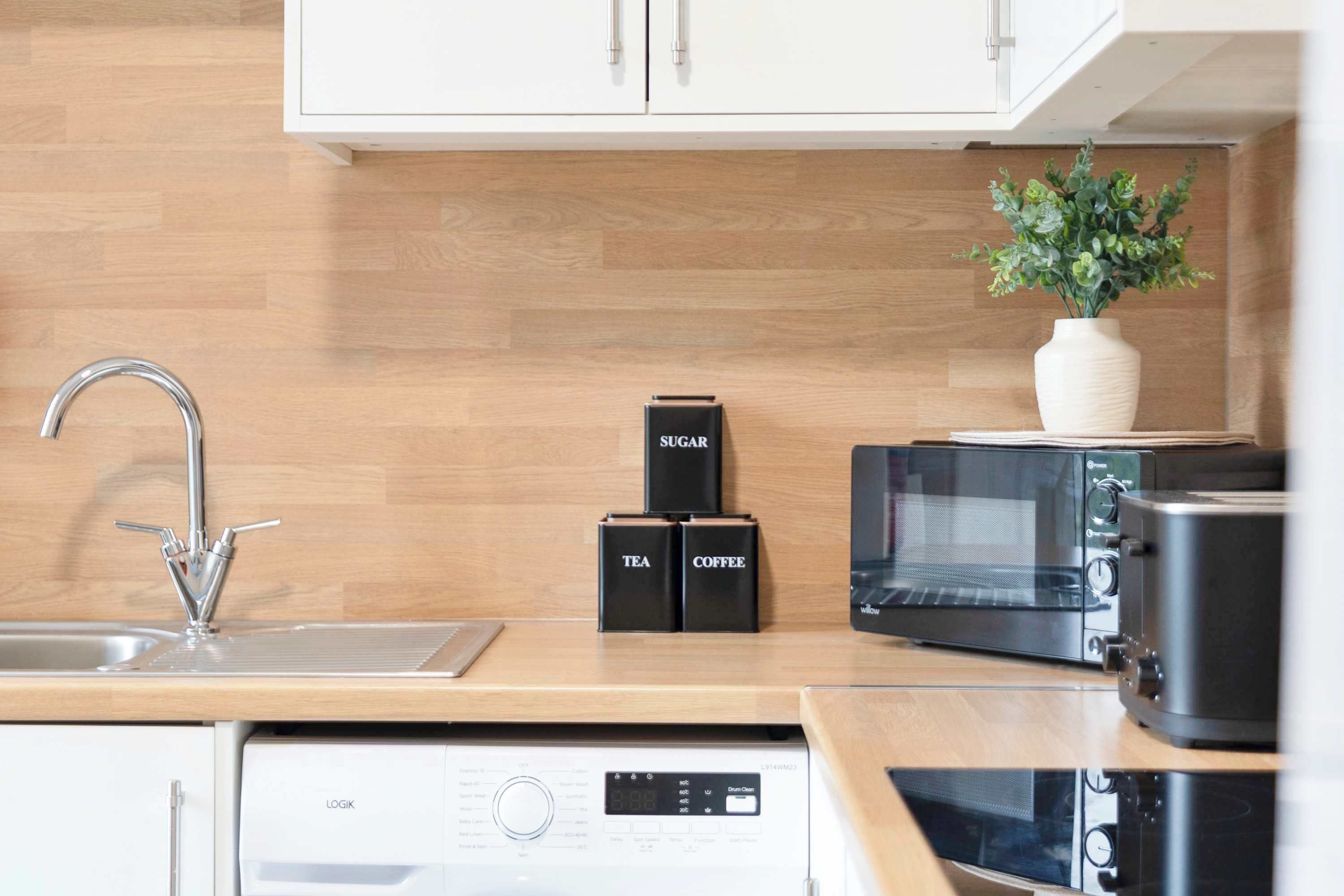 Una cocina moderna con lavavajillas integrado, microondas y cafetera.