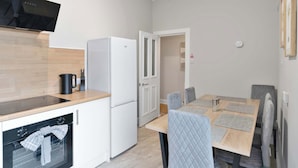 A compact kitchen with a built-in oven, a refrigerator, and a flat-screen TV. - Spacious 3BR Hawick Apartment, Sleeps 6, Parking (Scottish Borders)