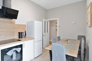 Eine kleine Küche mit integriertem Backofen, einem Kühlschrank und einem Flachbildfernseher.