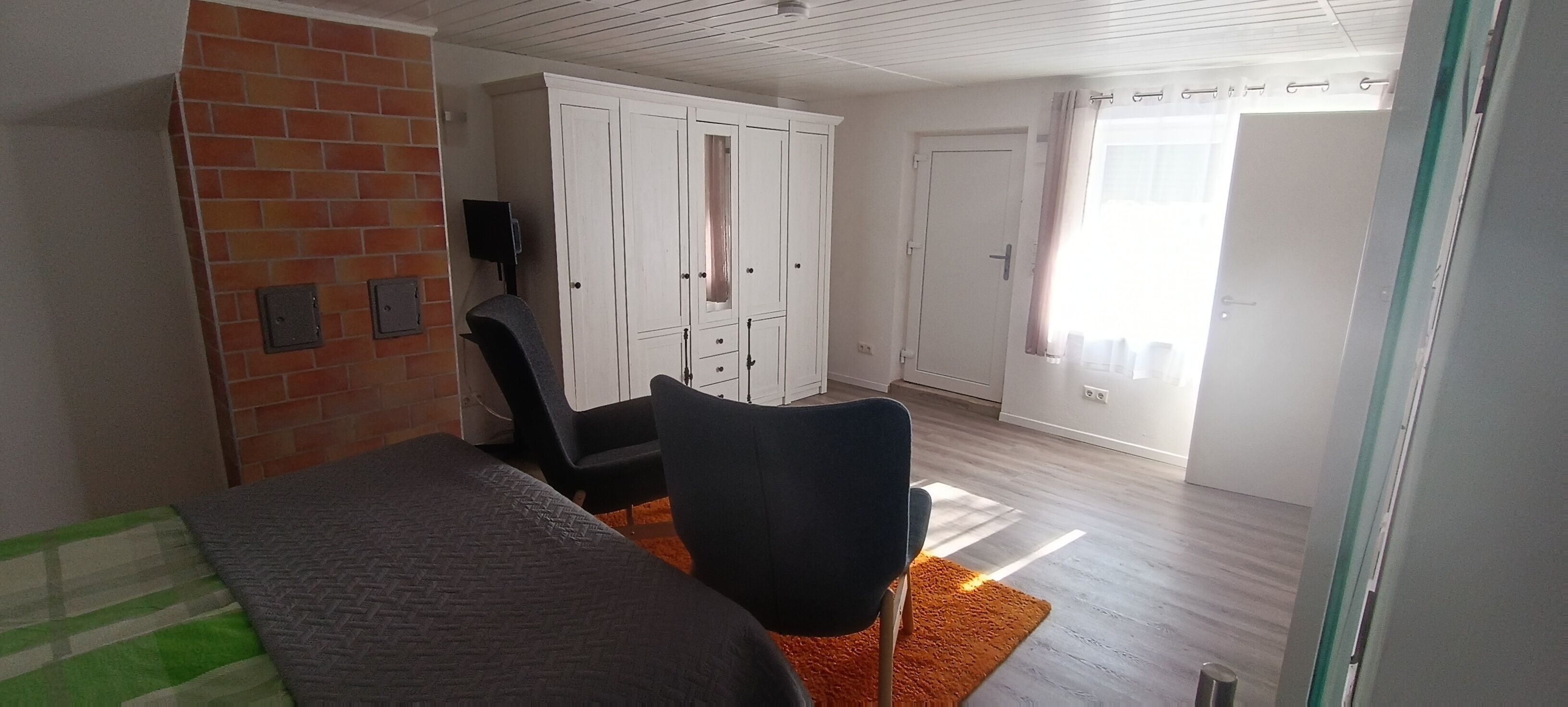 Une chambre à coucher comprenant un lit, un bureau, une chaise, une armoire et une fenêtre avec des rideaux.
